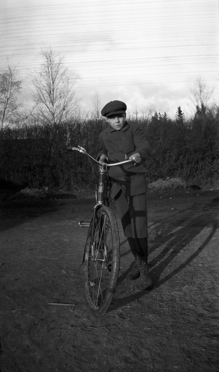 Ukjent gutt med sykkel på en vei. 