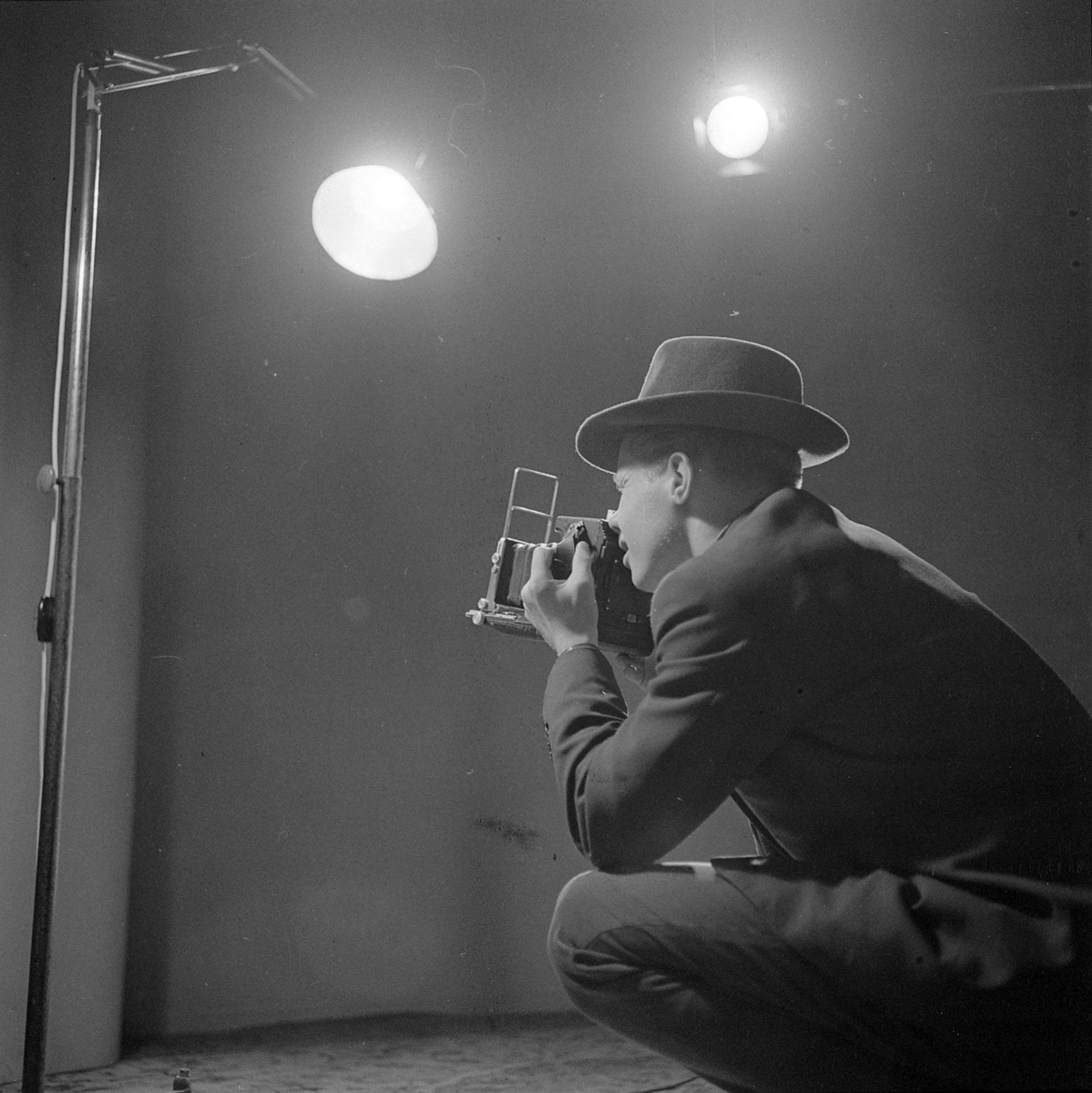 Fotograf med Speed Graphic pressekamera i fotostudio