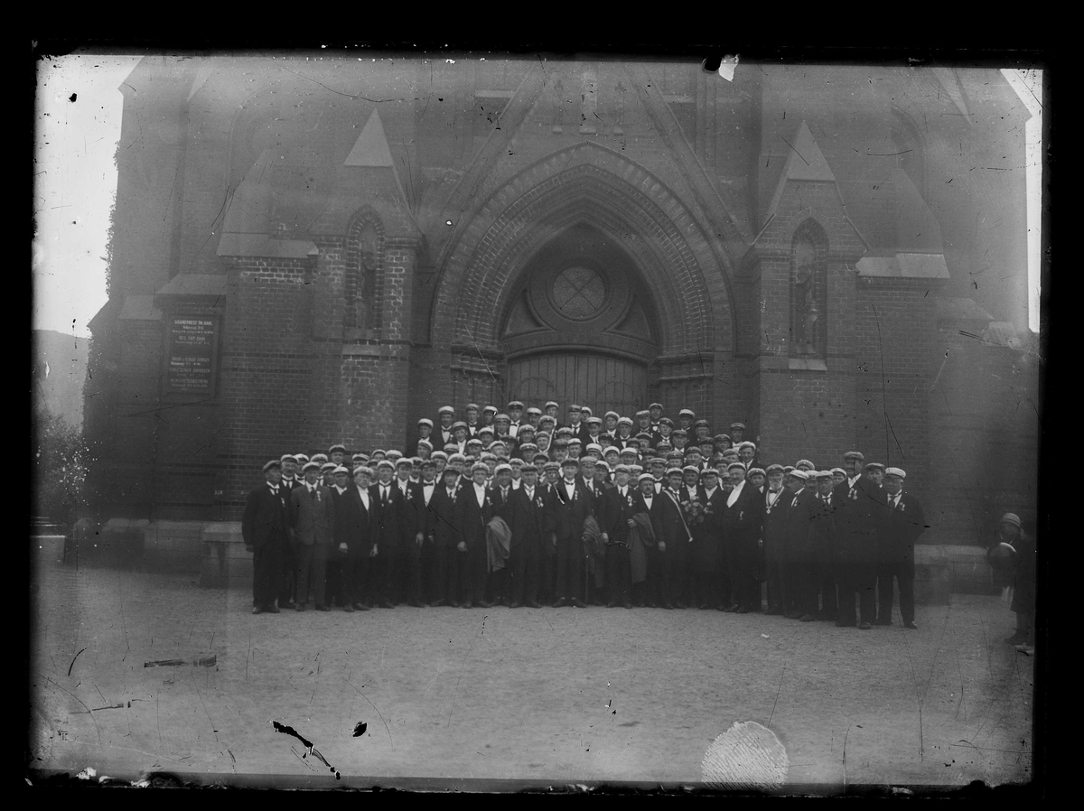 Medlemmer fra ulike mannskor, deriblant medlemmer av Røros Sangforening, samlet foran ingangen til en kirke.