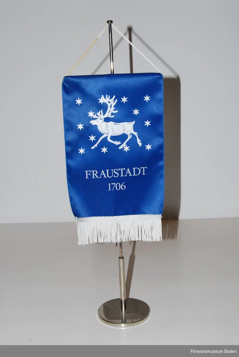 Norrbottens regemente I 19:s vapenbild med vit ren och stjärnor samt texten "Fraustadt 1706" på blå bakgrund. Inget motiv på baksidan. Fot med gravyren "Klubb 19 Garnisonsmuseet 17/6 1988 Nr 7.