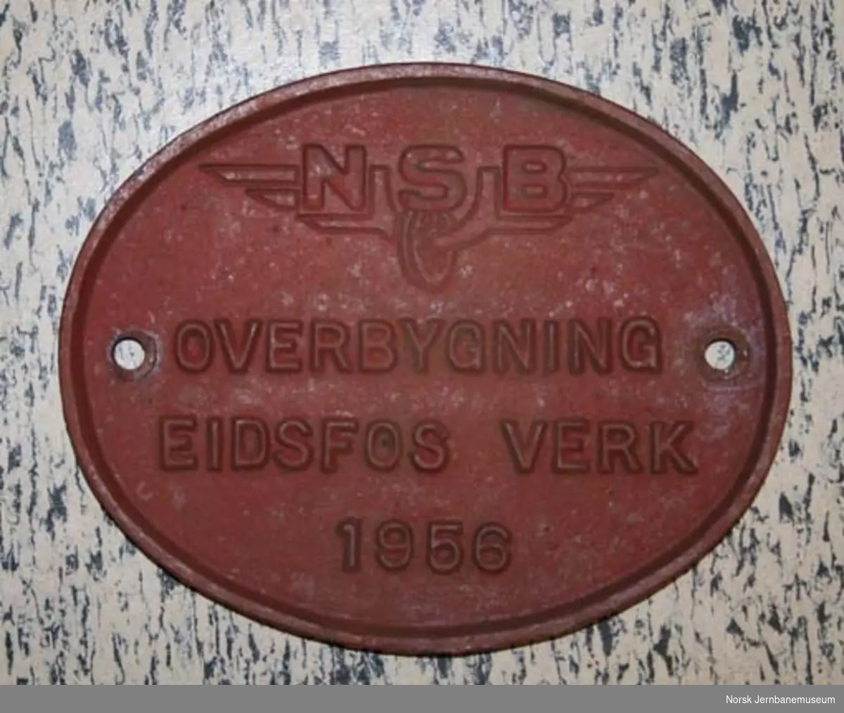Fabrikkskilt fra Eidsfos Verk : "Overbygning Eidsfos Verk 1956" og NSB-vingehjul