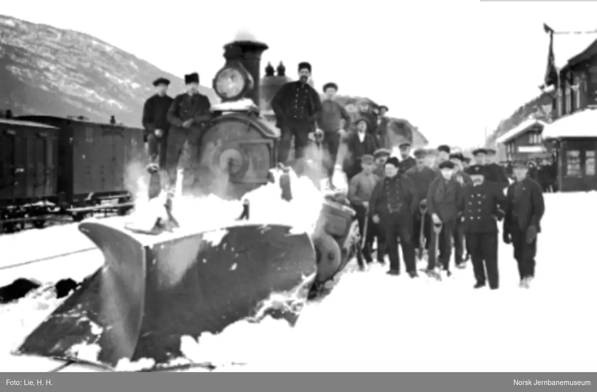 Damplokomotiv type 11 med stor frontplog og en gjeng snømåkere på Vinstra stasjon