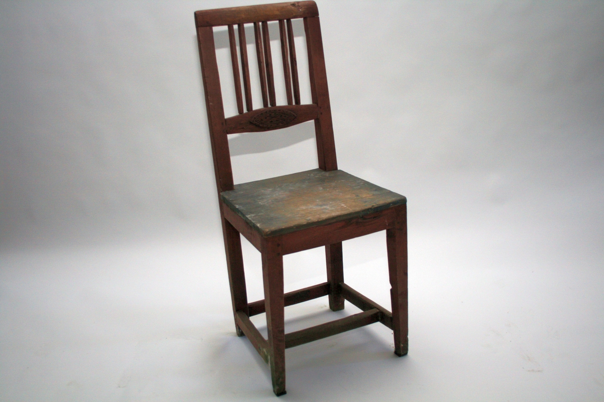 Rødmalt stol med 6 dobbeltstilte vertikale spiler i ryggen, og utskåret oval i horisontal ryggspile. 
En av to like stoler.