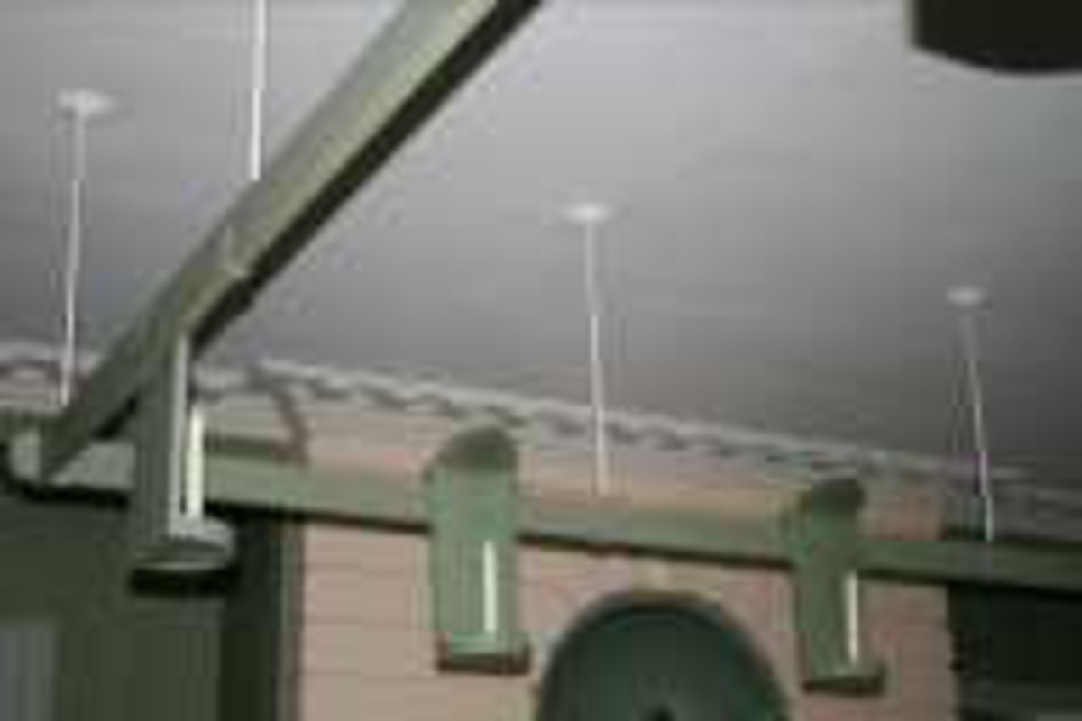 Treramme montert i taket. 10 lysholdere i blikk henger på ramma. Alt er grønnmalt.