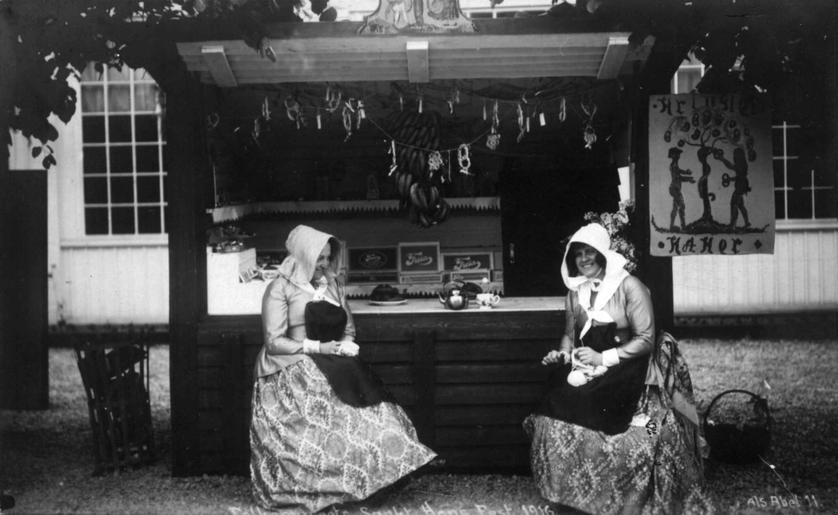 St. Hans feiring på Norsk Folkemuseum i 1916. To damer i drakt foran salgsbod.