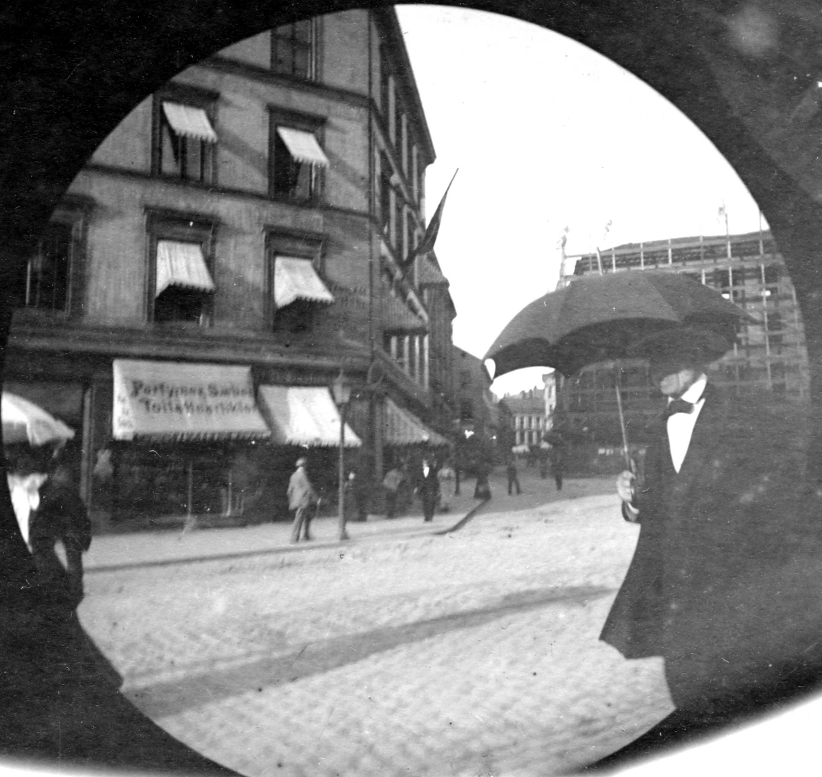 Statshauptmand H. Astrup spaserer i bygate, Oslo med paraply.