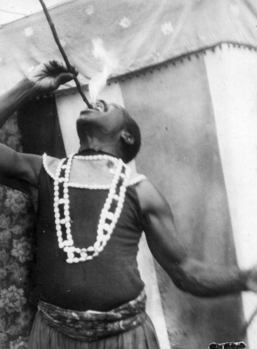 Marked på Norsk Folkemuseum i 1925. En svart mann sluker flammer foran et telt.
