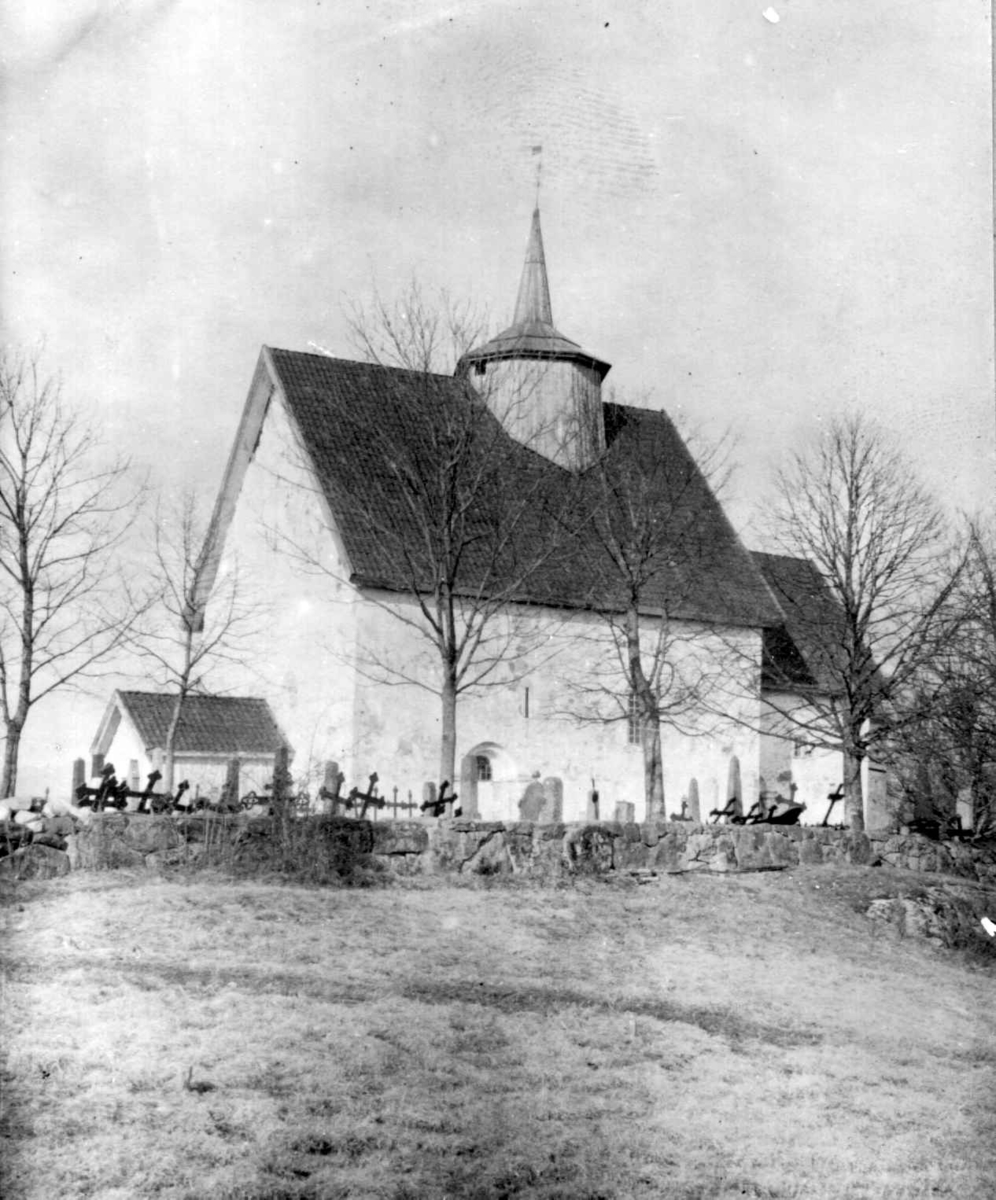 Eksteriørfoto av Bø gamle kirke med kirkegård og gravstøtter.