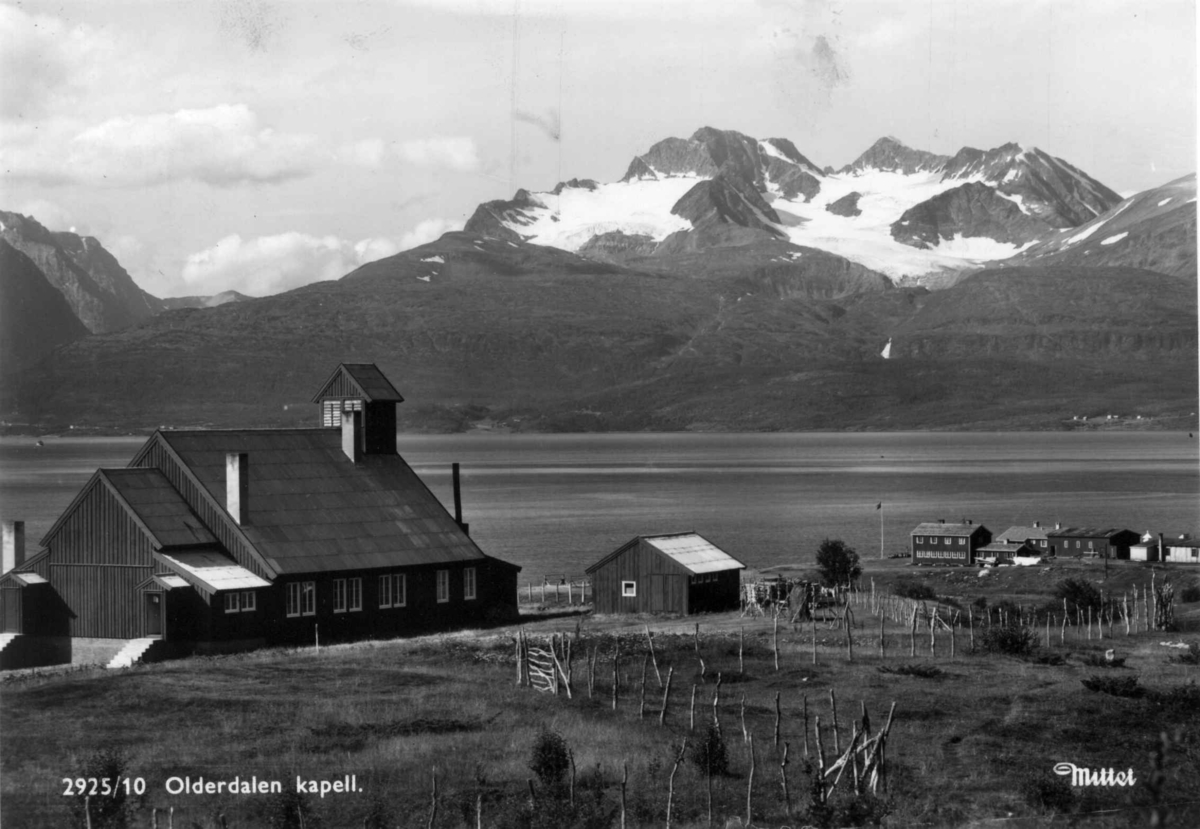 Olderdalen kapell og bebyggelse med fjord og fjell i bakgrunnen.