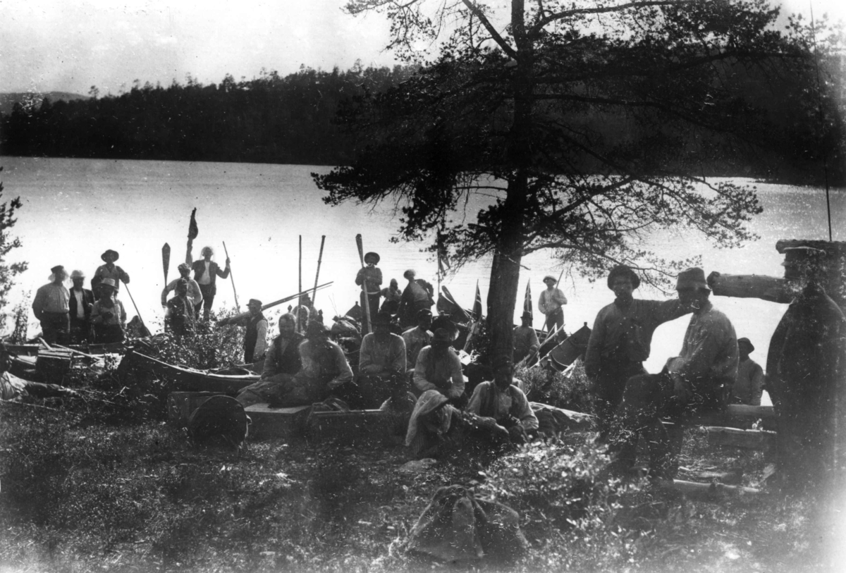 Fra grenseoppgang i Sør-Varanger, Finnmark, antatt 1897-1899. Gruppe mennesker med båter samlet ved vannkanten.