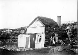 Bolighus, ukjent sted, med panelt gavlside med steinvegger b
