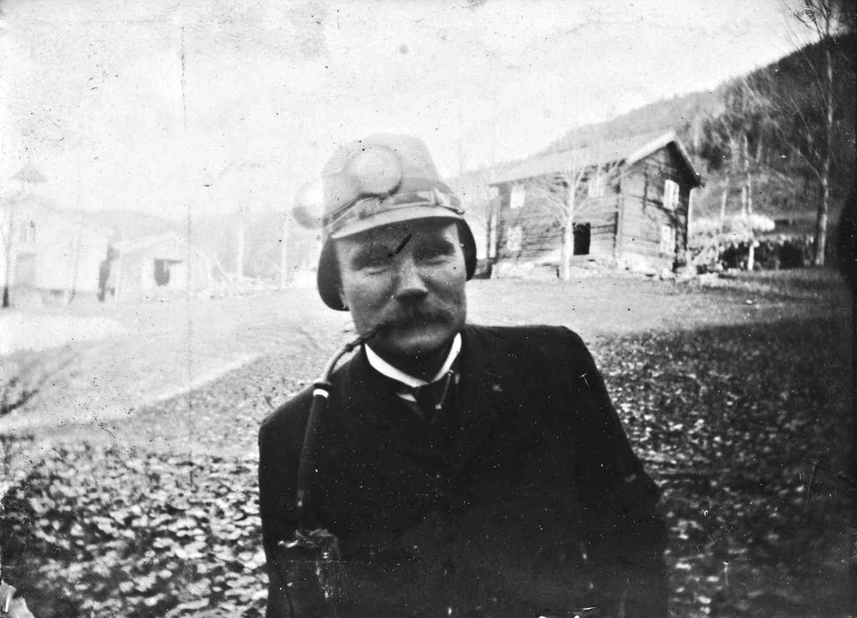 Mann med hjelm og langpipe på gårdstunet, Lunden gård, Hegglandsgrend, Fyresdal, Telemark.