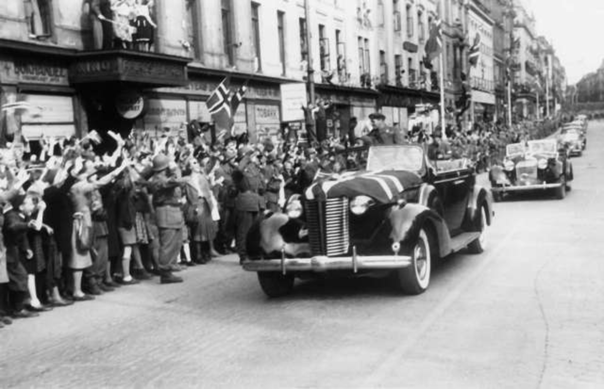 Fra Oslo under fredsdagene i 1945.
Den 13.mai kommer Kronprins Olav tilbake.Kortesjen kjører oppover Karl Johans gate i retning Slottet.Kronprinsen sitter på kalesjen og hilser til de fremmøtte.