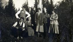 En gruppe ungdom foran flaggstang, En spiller mandolin. Ca 1