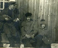 To menn og en kvinne, en av mennene spiller mandolin. Ca. 19