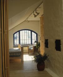 Soverom med buet vindu i utbygd loft i en gammel bygård. llu