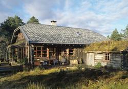 Et hus og et gjestehus ligger vakkert i terrenget i Naustdal