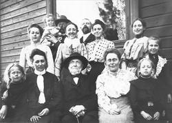 Familieportrett, stor gruppe mennesker foran bygning.
Famil