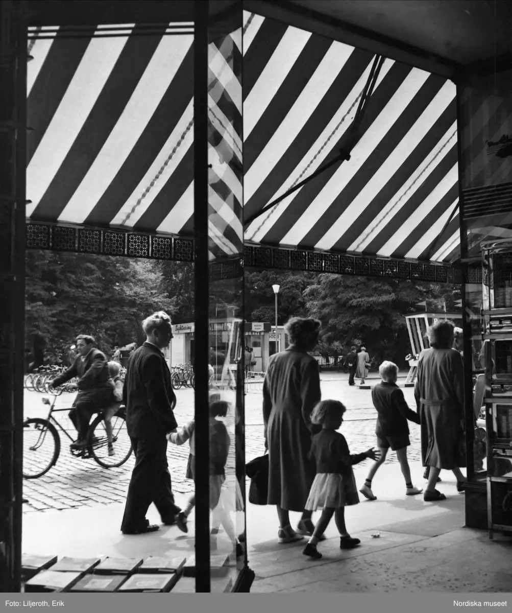 Flanerande människor och en man som skjutsar en pojke på sin cykel på Gustaf Adolfs torg, Malmö.