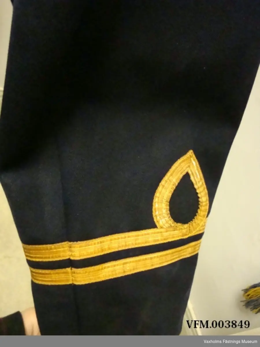 Uniform, kolett och byxor i blått kläde m/02, med löjtnants gradbeteckning. På höger ärm flygtecken m/15 (flygspanare)