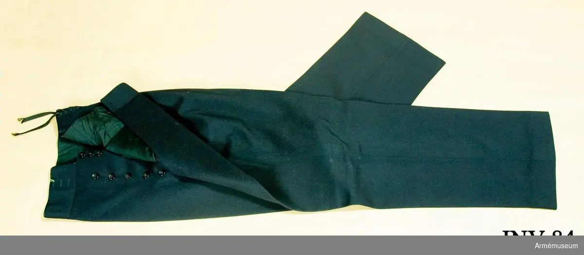 Av mörkblått kläde. Fodrad i livet med svart siden. Två sidofickor. Snörning bak. Tolv bakelitknappar i gylfen.
Har tillhört Gustav VI Adolf (1882-1973). 
