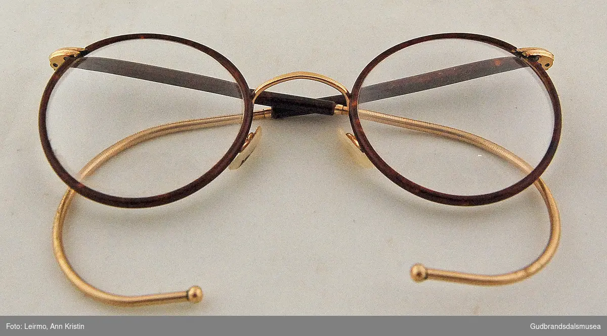 "Hornbriller" med runde glass og bøyde stenger til å feste bak øret. 