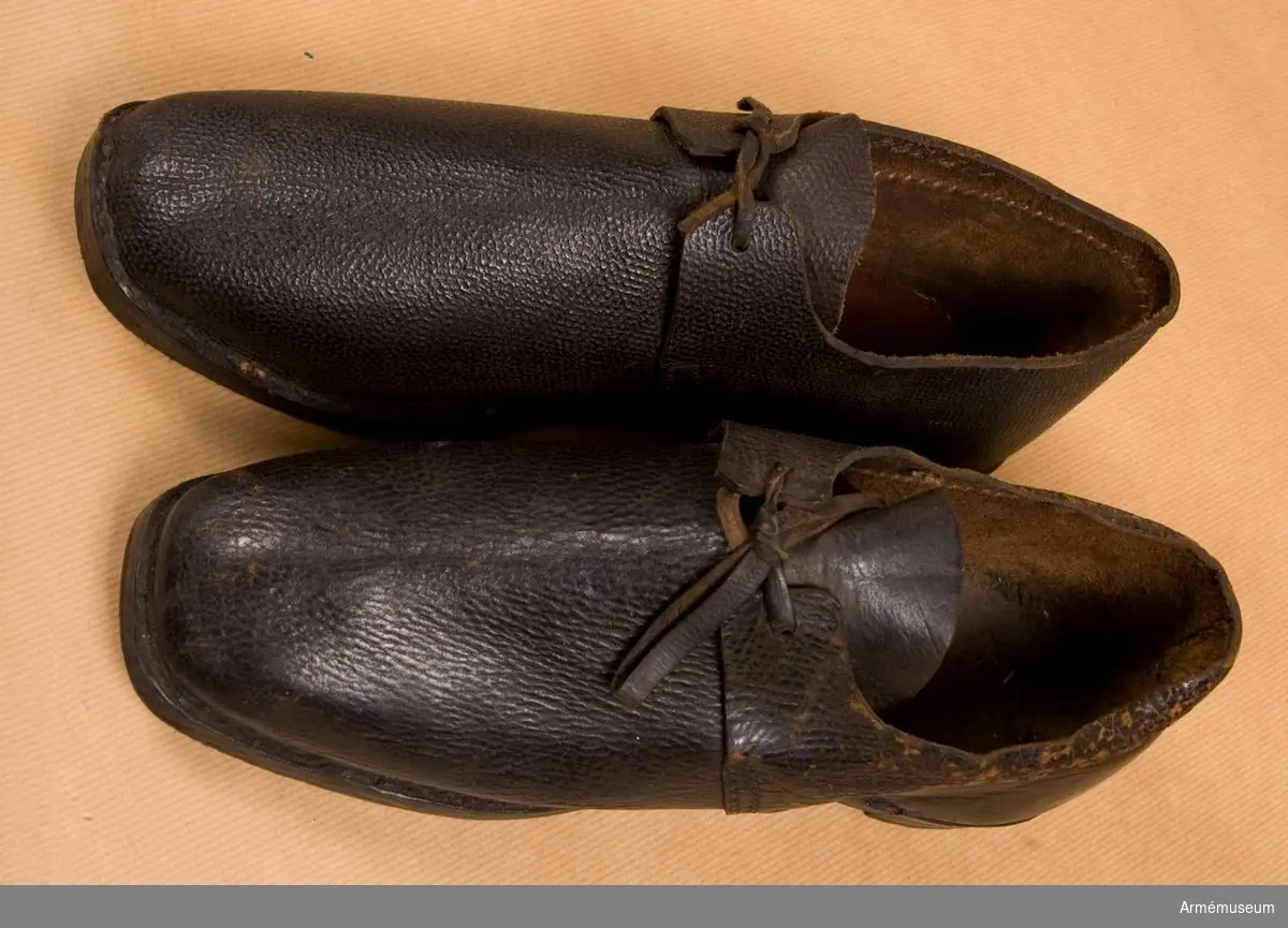 Skor av brunt läder.
Den ena skon har spår av rött lacksigill och är därför ett modellexemplar. Den andra skon är med största sannolikhet en replika.