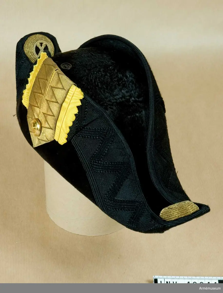 Grupp C I.
Trekantig hatt m/1854. Ur uniform för överstelöjtnant vid Fortifikationen, bestående av  vapenrock, epåletter, hatt med plym, mössa, kask med plym,  skärp.