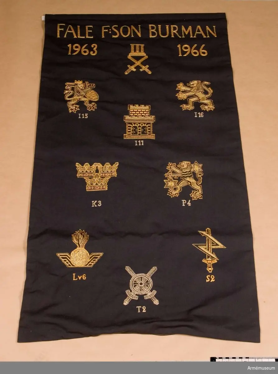 Minnesbonad broderad med de heraldiska vapnen för arméförbanden inom det III militärdistriktet, namnet på dess chef Fale F:son Burman, och årtalen 1963 och 1966.