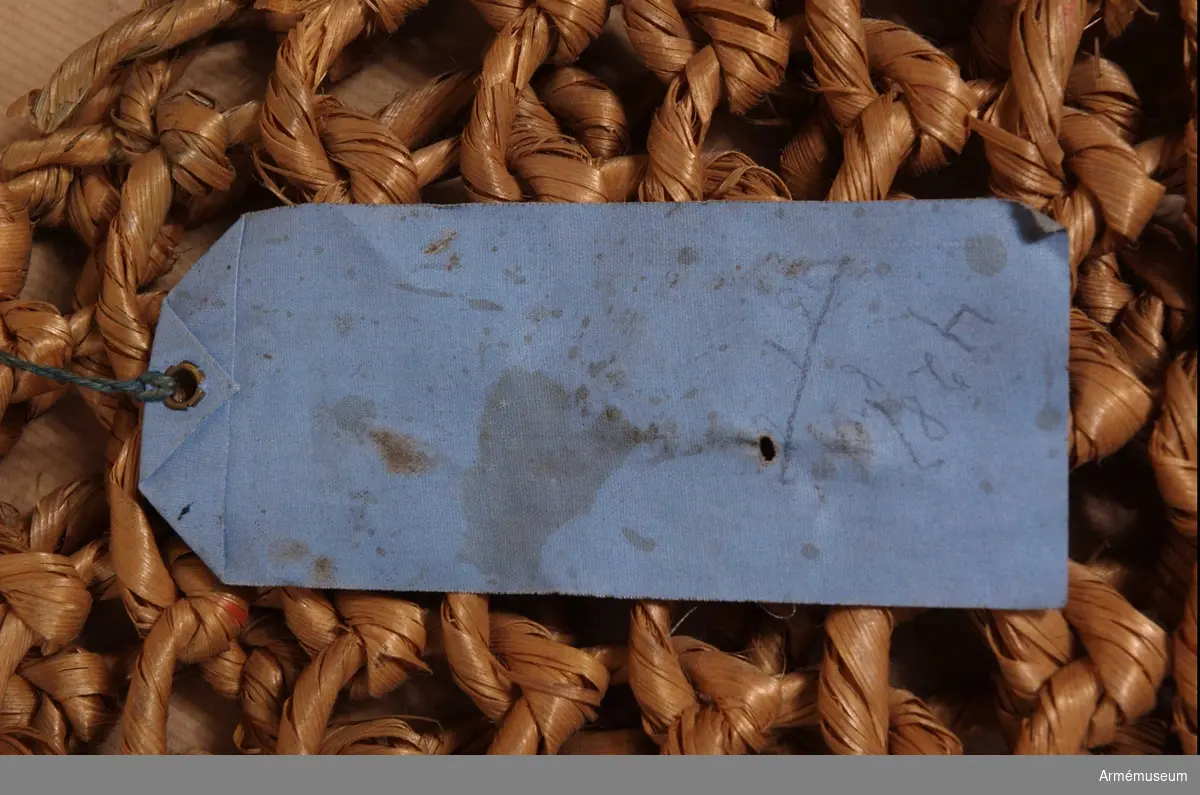 Kasse tillverkad av träbast bunden i runda maskor. Vidhängande blå pappersetikett med text: "No 4 Träkasse för kött, för infanteriet, kavalleriet och trängen. Sven Odquist, tygkapten"  KTS 2012-02-01