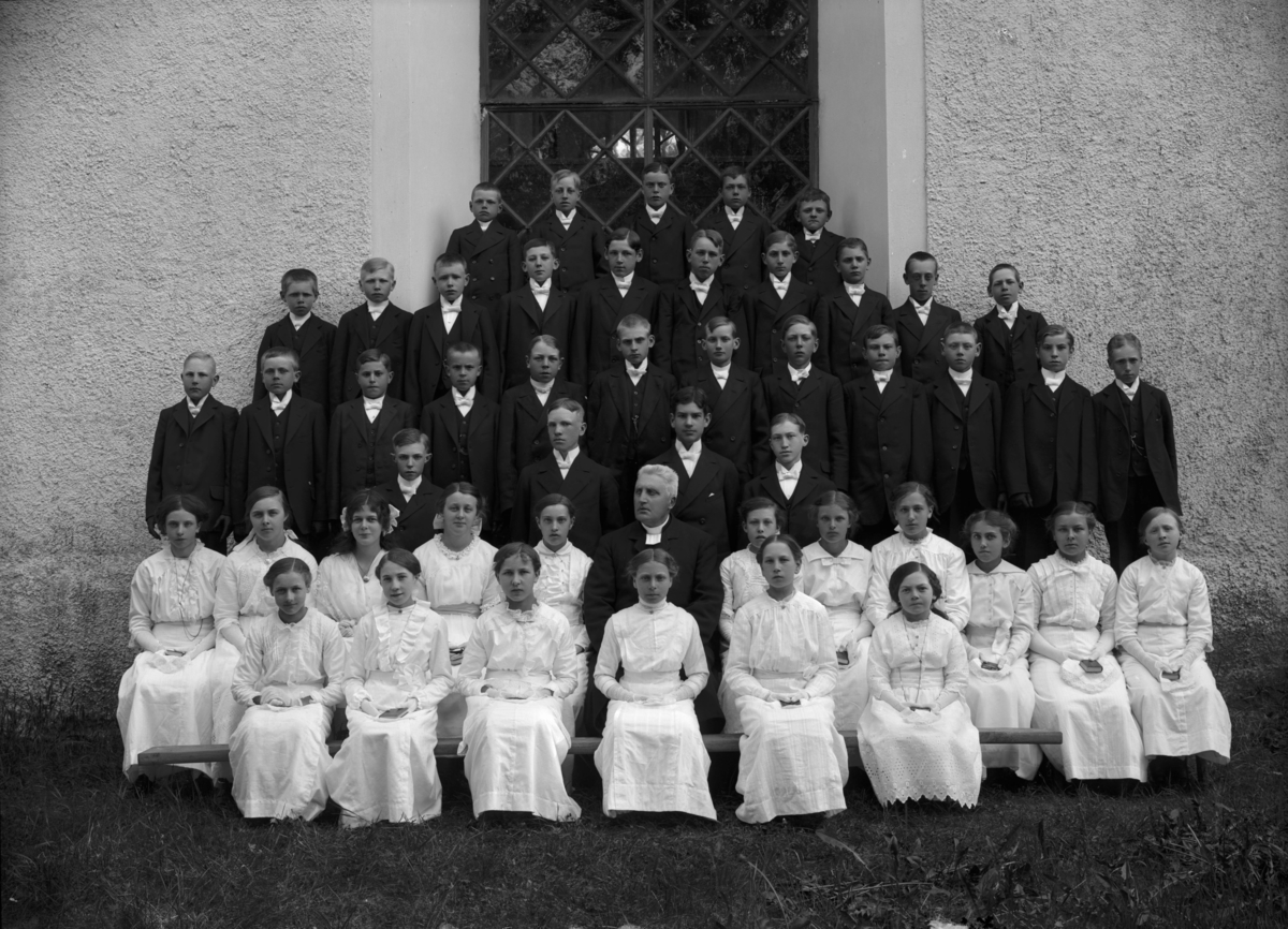 Konfirmandgrupp vid Simtuna kyrka, Uppland, 23 juni 1915. I mitten kyrkoherde August Hylander (1852-1935).