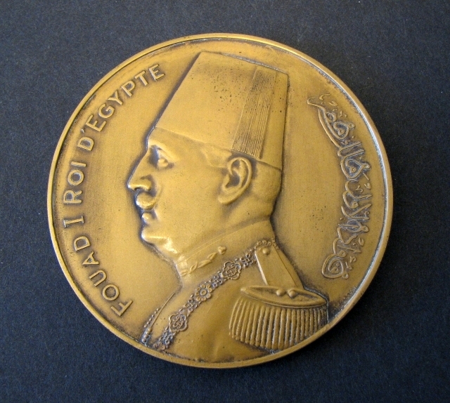 Medalj i brons, rund, präglad med anledning
avVärldspostföreningens kongress i Kairo, Egypten år 1934. På
åtsidanett porträtt i profil av Egyptens kung Fouad I, samt text
enligt MRK.Frånsidan visar en avbildning av Världspostmonumentet i
Bern, Schweiz.