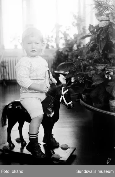Pojke sittandes på en leksakshäst. Förmodligen Clas Fredrik Hans Torsten Norström f 1915, barn till Lennart och Pussi Norström.