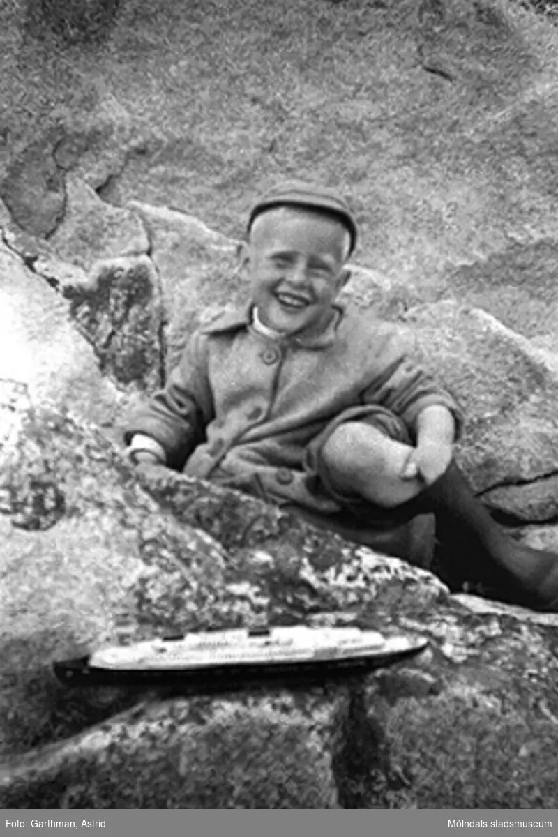 Alf Garthman sitter och leker med sin leksaksbåt bland klipporna vid Näset, 1953-54.