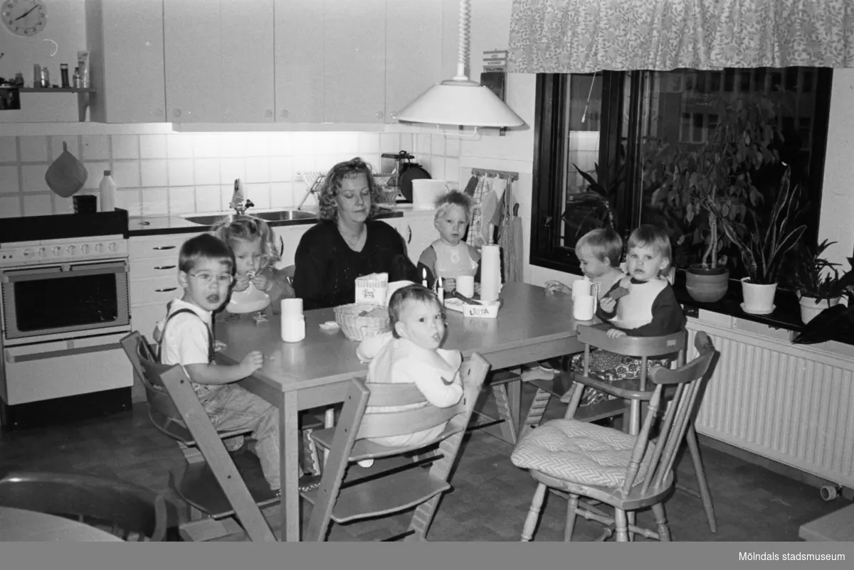 Anita Nylén och sex dagisbarn (Natasha längst till höger) sitter runt ett köksbord och äter. Två barn sitter på var sin Tripp Trapp-stol.