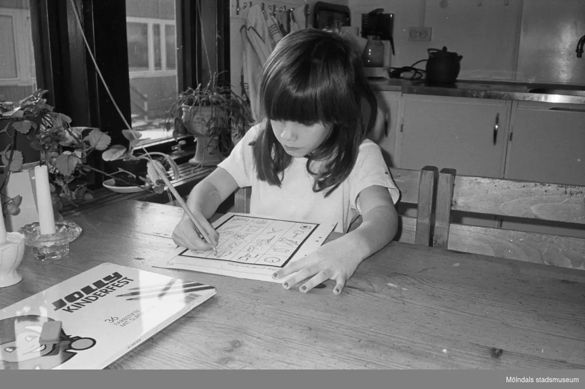 Cecilia sitter vid ett bord och färglägger med hjälp av färgpennor, förtryckta figurer på ett A4-blad. Flickan är mycket koncentrerad. Lunkentussen, Katrinebergs daghem 1992.
