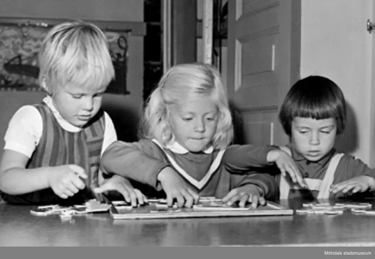 Tre flickor som hjälps åt med ett pussel. Holtermanska daghemmet 1953.