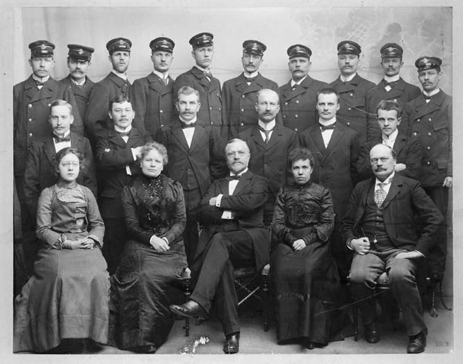 Gruppfotografi av personalen vid paketexpeditionen på
Postkontoret Stockholm 1, vid Rödbodtorget år 1902.

Tredje fr.v. i andra raden är ebtr N.W. Höglund.  I första raden nr
3 är px F.A. Beijbom, nr 4 är t.f. px Ottilia Lewysohn.