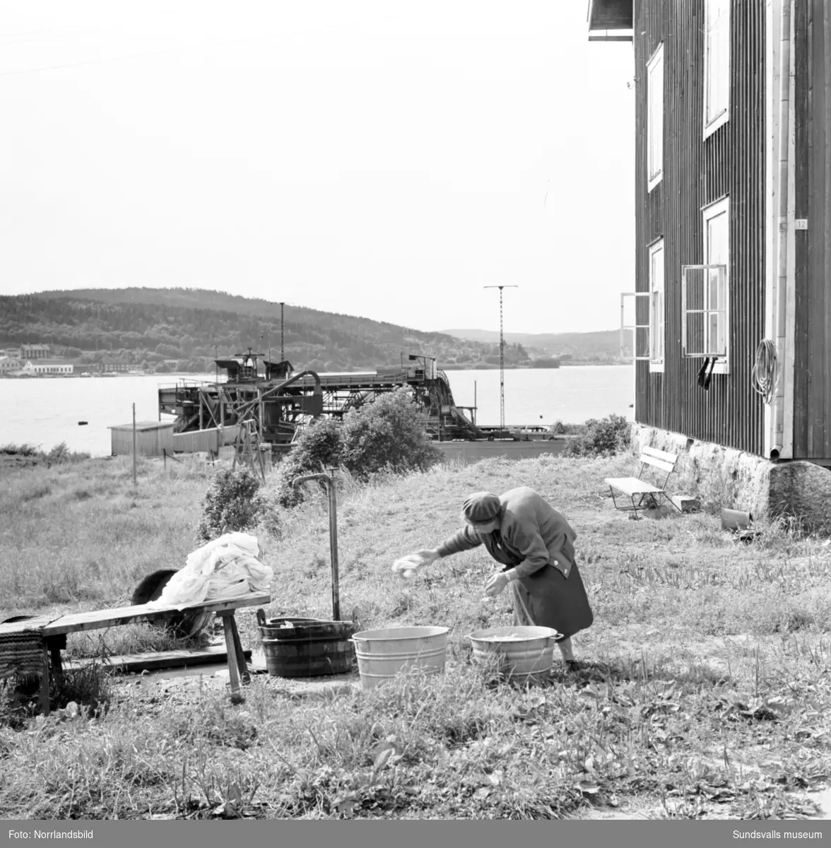 Reportagebilder från Alnö tagna för Expressen. En äldre dam som tvättar utomhus, sågverksbilder, färjan med mera.