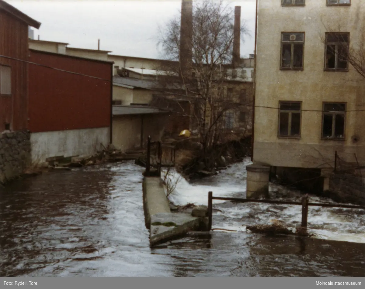 Vy västerut från Rackarebron över Mölndalsfallen, 1970-tal. Till vänster ses ett gammalt magasin från 1800-talet och till höger byggnaden "Strumpan" (efter Viktor Samuelsons fabrik), Kvarnbygatan 10-14.