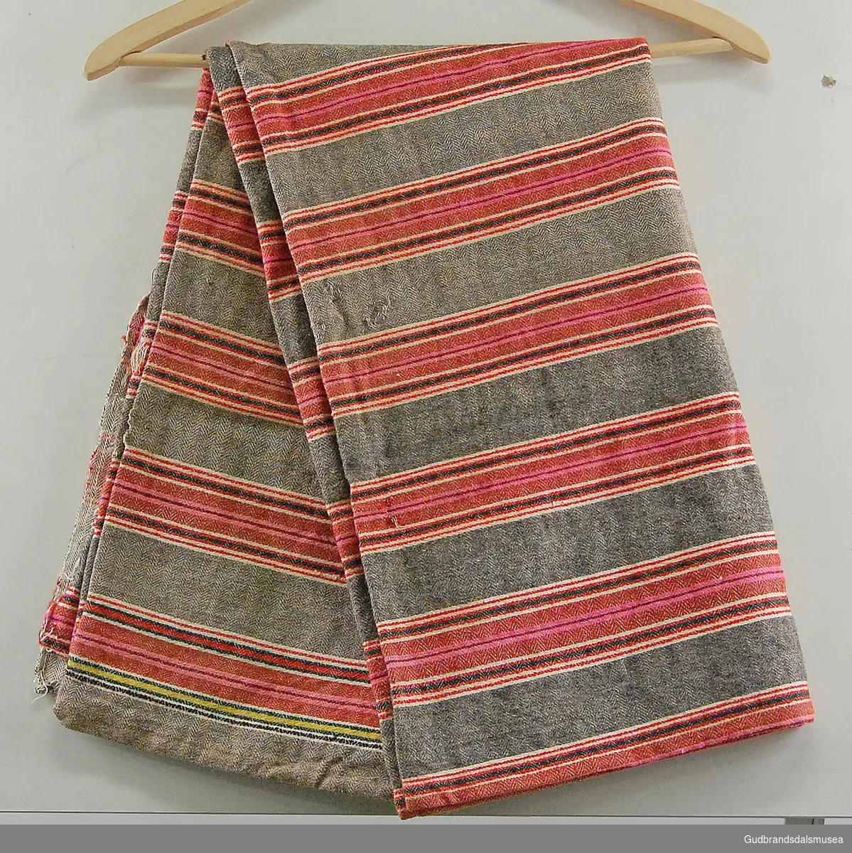 Stort rektangulært putevar i vevd ull. Vertikale striper i ulike farger. Åpning på ene kortsiden som fortsetter et stykke langs ene langsiden. 