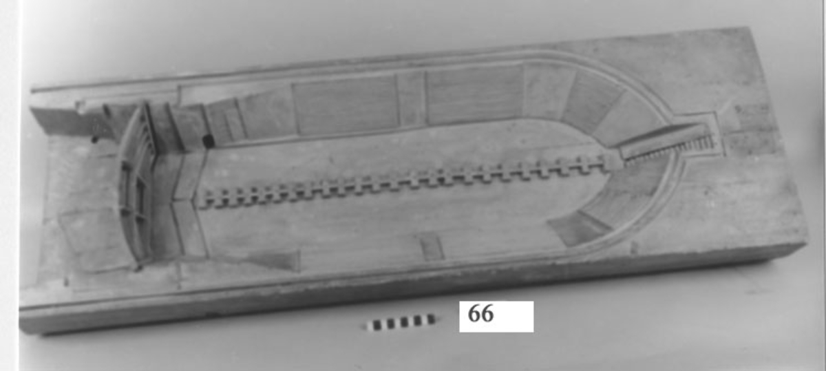 Modell av torrdocka, tillverkad i tre stycken, med delvis trappstegsformade långsidor och ett uttag längst in för fartygens stäv samt med dockport i ett stycke.
Av trä, gråmålad.