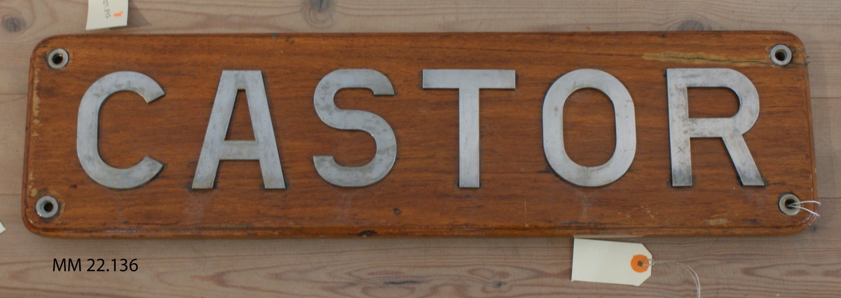 Namnbräda av trä med bokstäver av rostfritt stål: Castor.