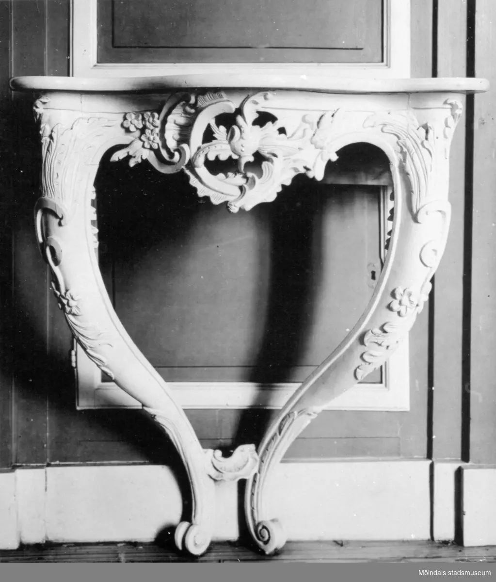 Dekorerat väggfast bord med avsmalnande, inåtgående ben. Gunnebo slott 1930-tal.