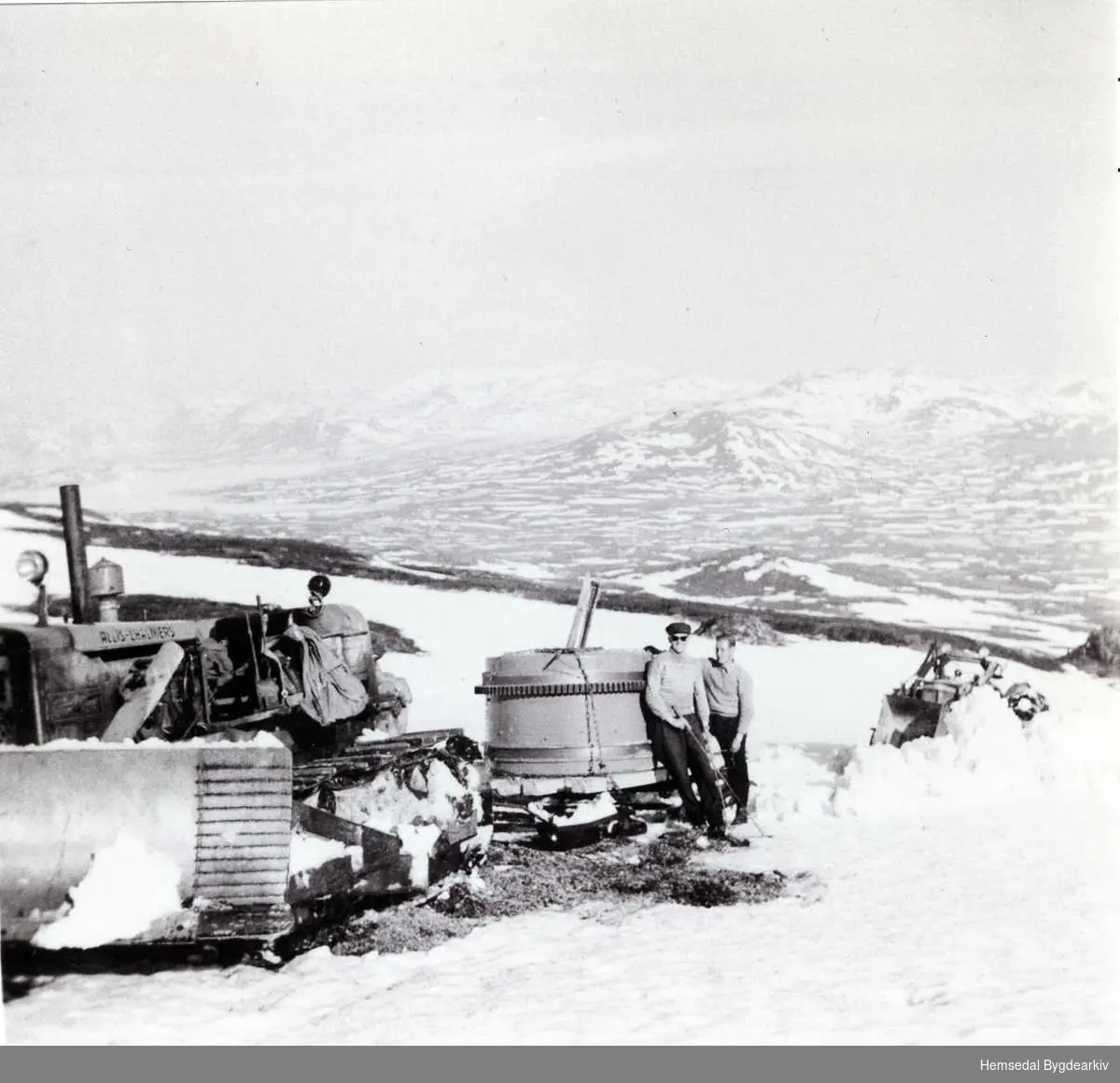 Innkøyring av bulldosar, traktor og utstyr i 1959 til arbeid med demminga av Dyrja på Feten i Hemsedal.
Her er ein på veg opp mot Systerskaret. Holdeskaret og Flævatn i bakgrunnen.