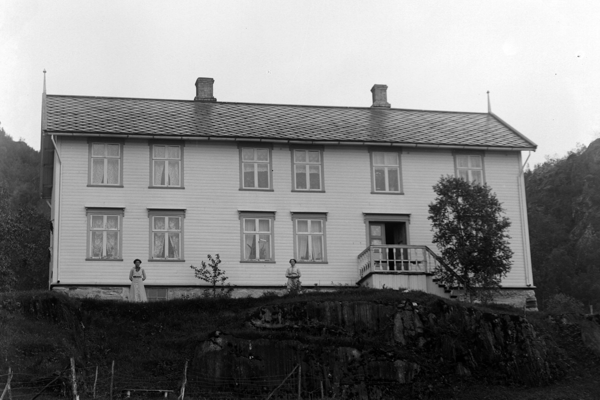 To kvinner foran et to-etasjers hus.