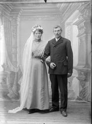 Studioportrett av et brudepar i helfigur.