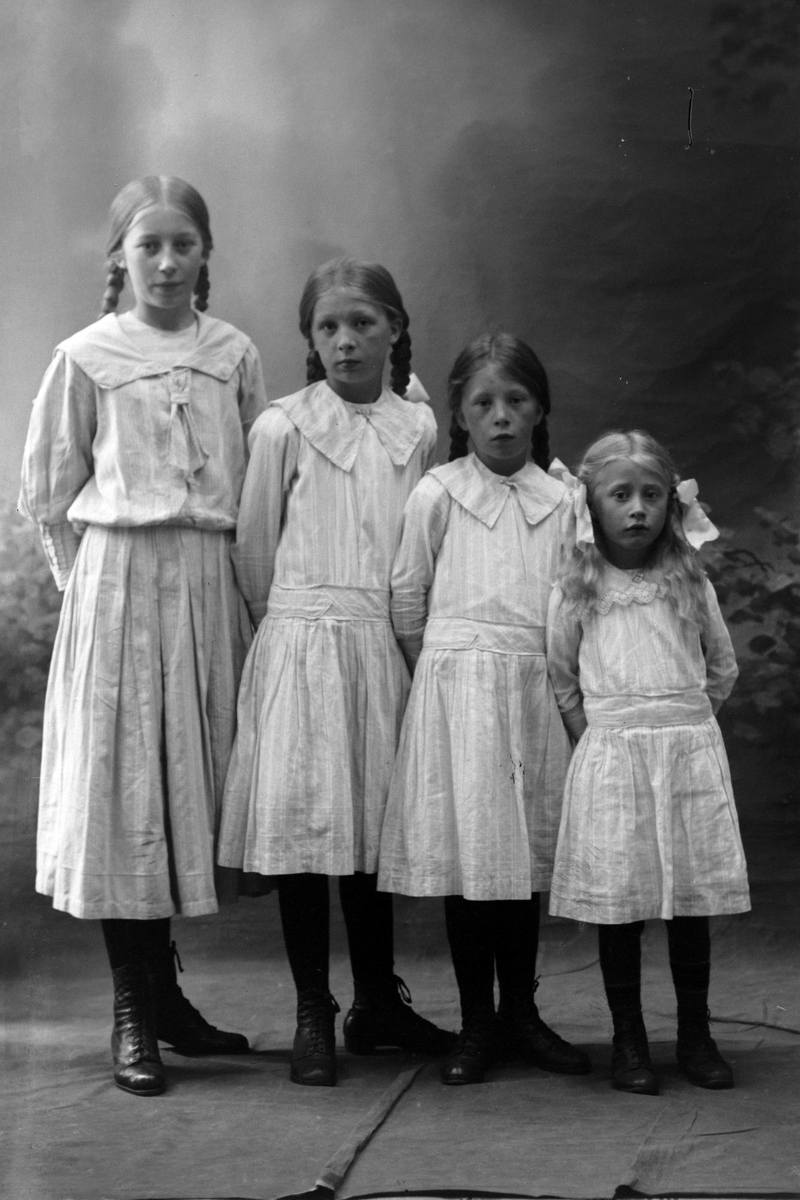 Studioportrett av fire jenter. Jentene er stilt opp etter høyde, med eldste til venstre og yngste til høyre.