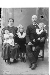 Studioportrett av en mann og kvinne med tre barn.