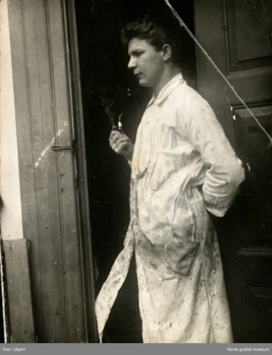 Mann i hvit arbeidsfrakk står i en døråpning og røyker pipe. Profilbilde. Fra Dreyers Reproduktionsanstalt i Stavanger.
Albumtekst: "Vareberg 1906" (Gunnar Wareberg).